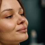 Satisfied beautiful girl after lip piercing beauty concept close-up face earring lip