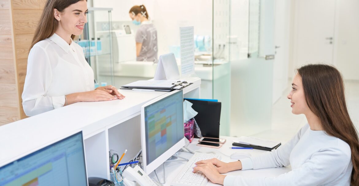 Pleased female patient communicating with friendly secretary in medical center