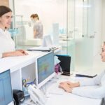 Pleased female patient communicating with friendly secretary in medical center