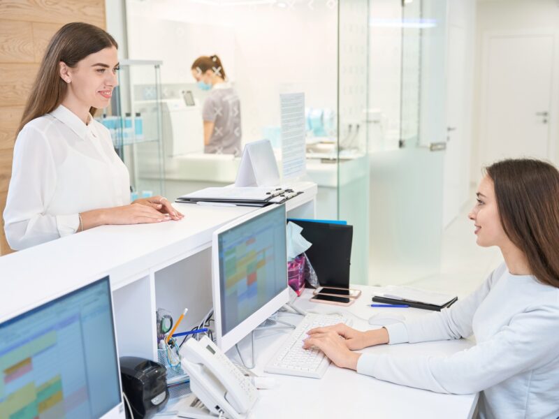Pleased female patient communicating with friendly secretary in medical center