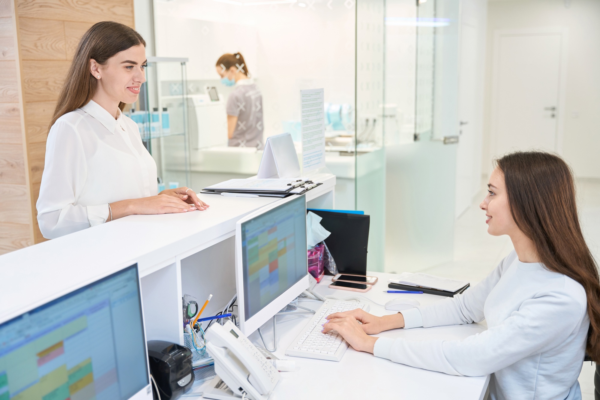 Pleased female patient communicating with friendly secretary in medical center