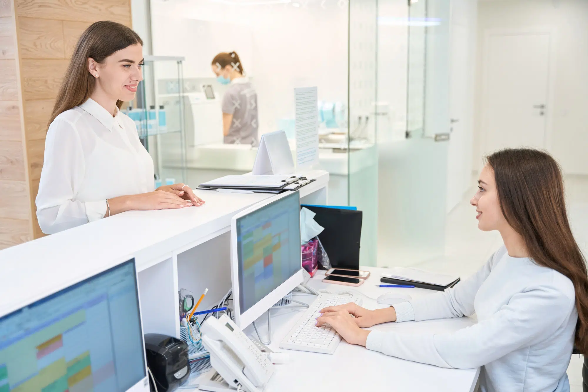 Pleased female patient communicating with friendly secretary in medical center