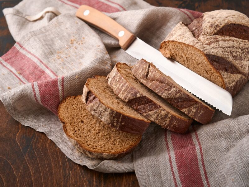 Fresh homemade rye bread. Traditional spelled sourdough bread cut into slices on a rustic wooden bac
